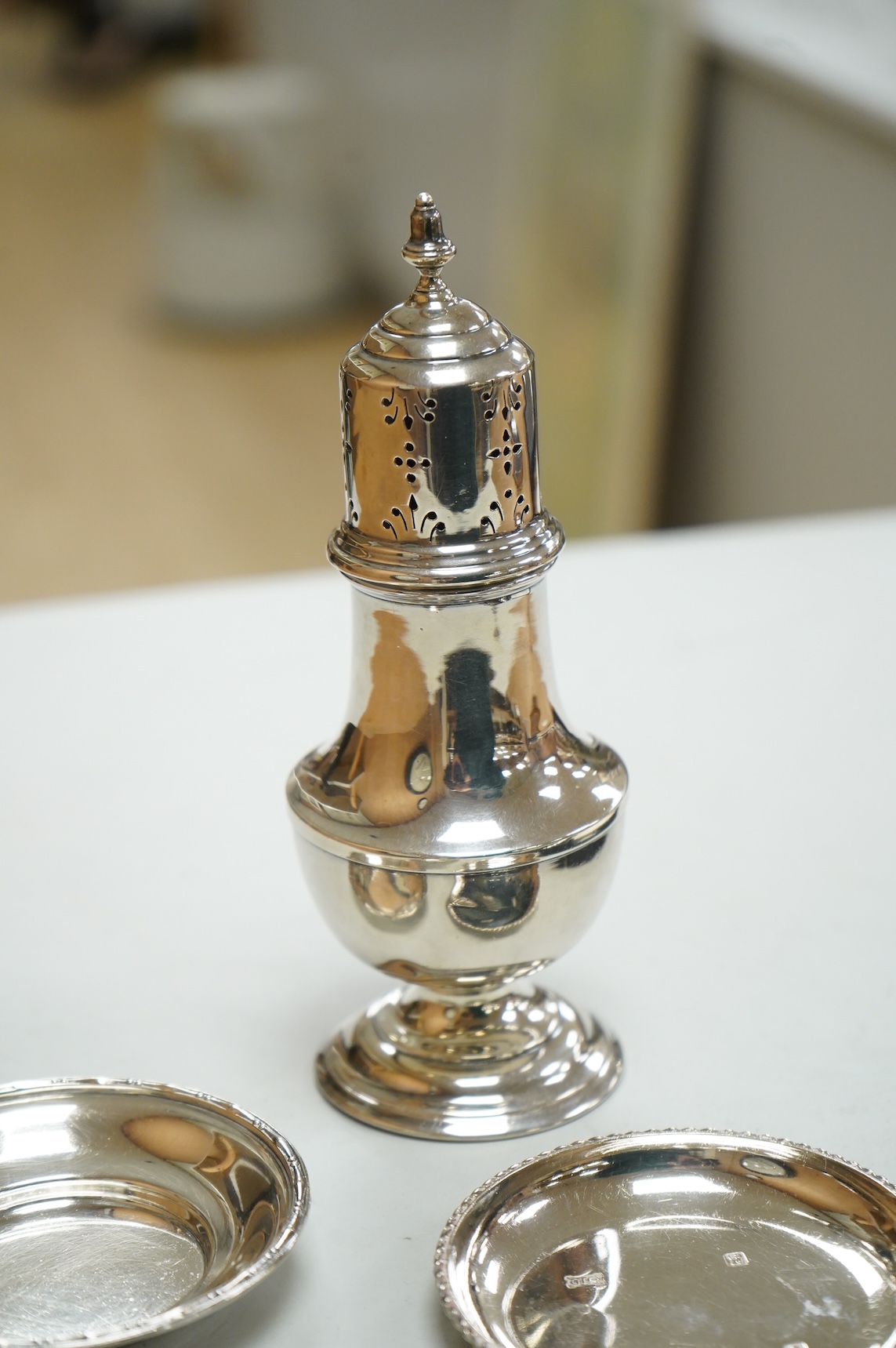 A George V silver sugar caster by Walker & Hall London 1932, 16cm, together with three silver nut dishes and a cased set of six silver coffee spoons.